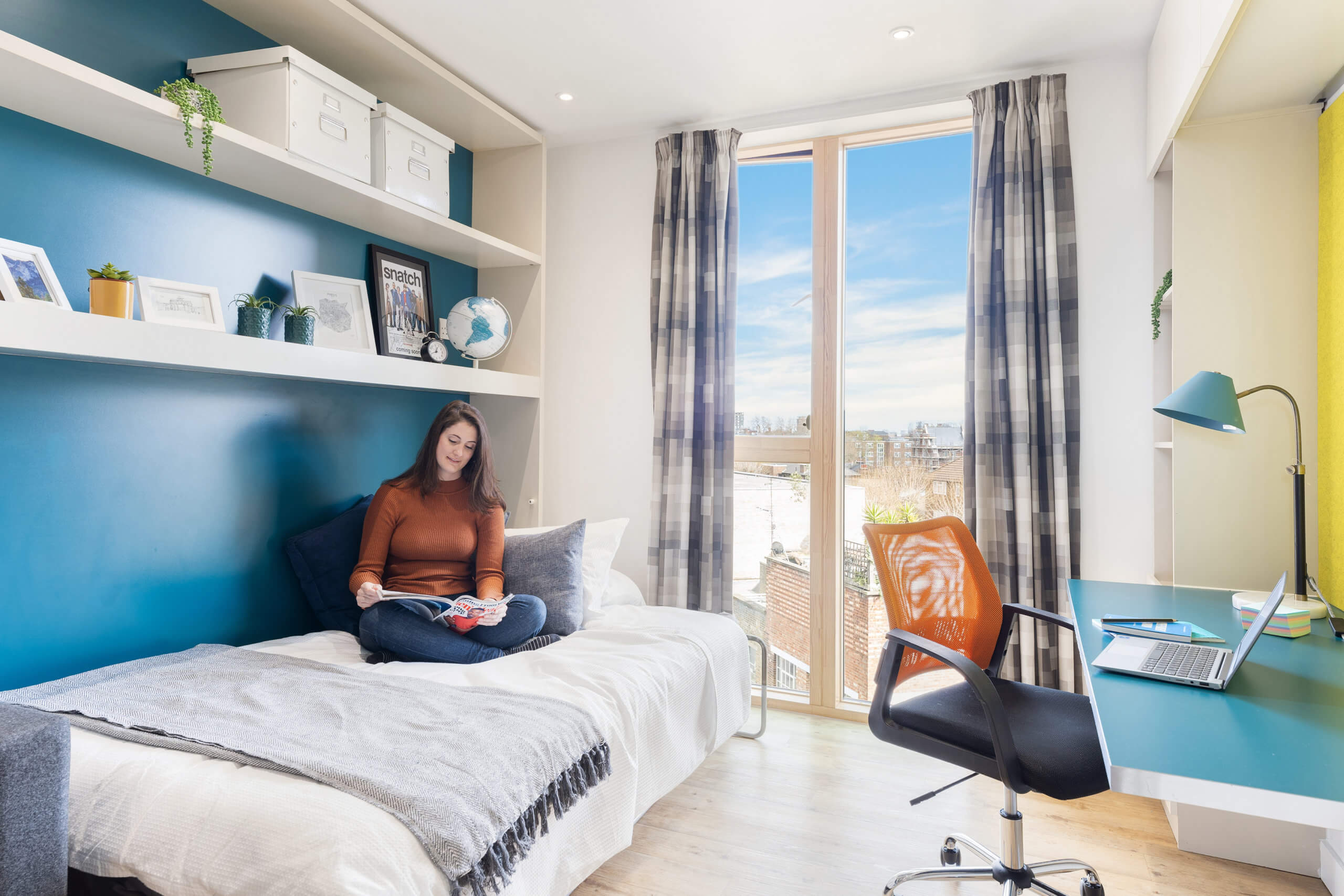 Young woman sat on bed reading in student accommodation Hoxton