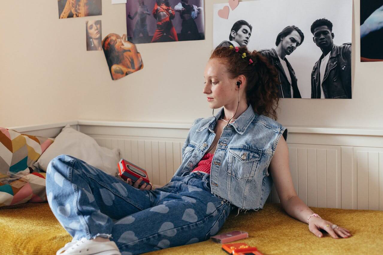 Girl sat on bed in student bedroom with posters in background