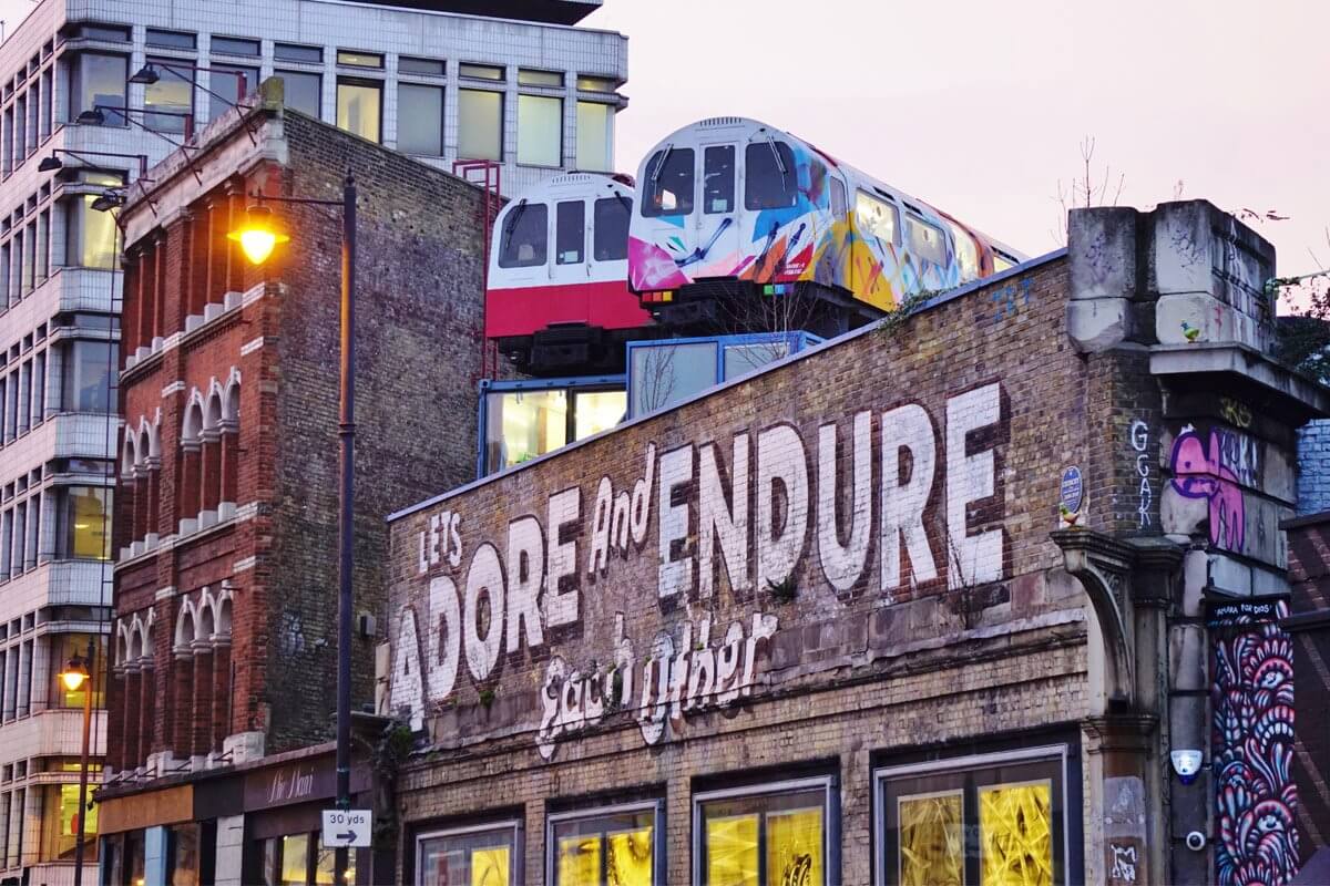 A picture of Hoxton architecture, featuring street art, discontinued rail trains, and various buildings.