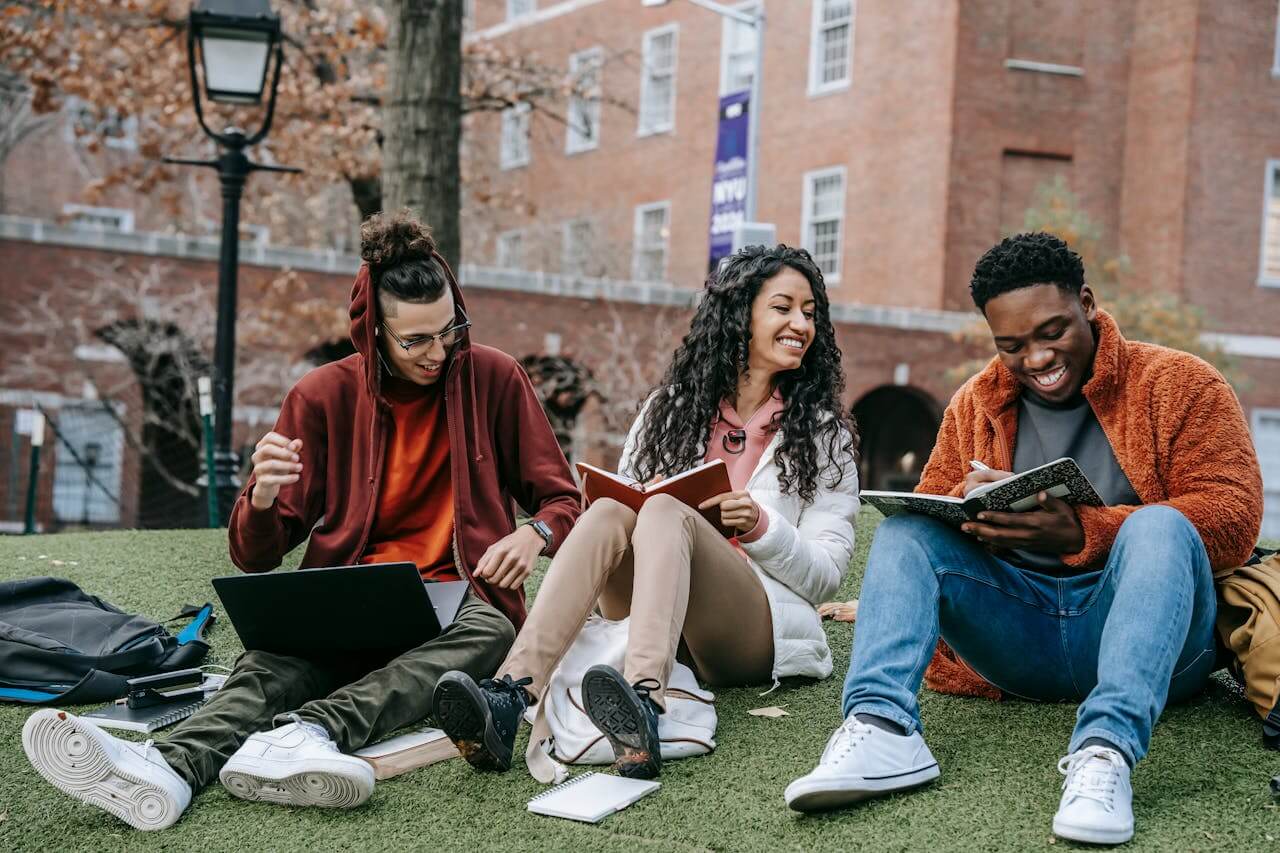 Three students socialising over books outside