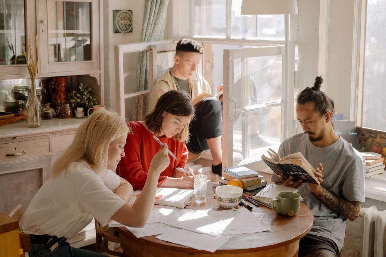 University Students sat around kitchen table studying