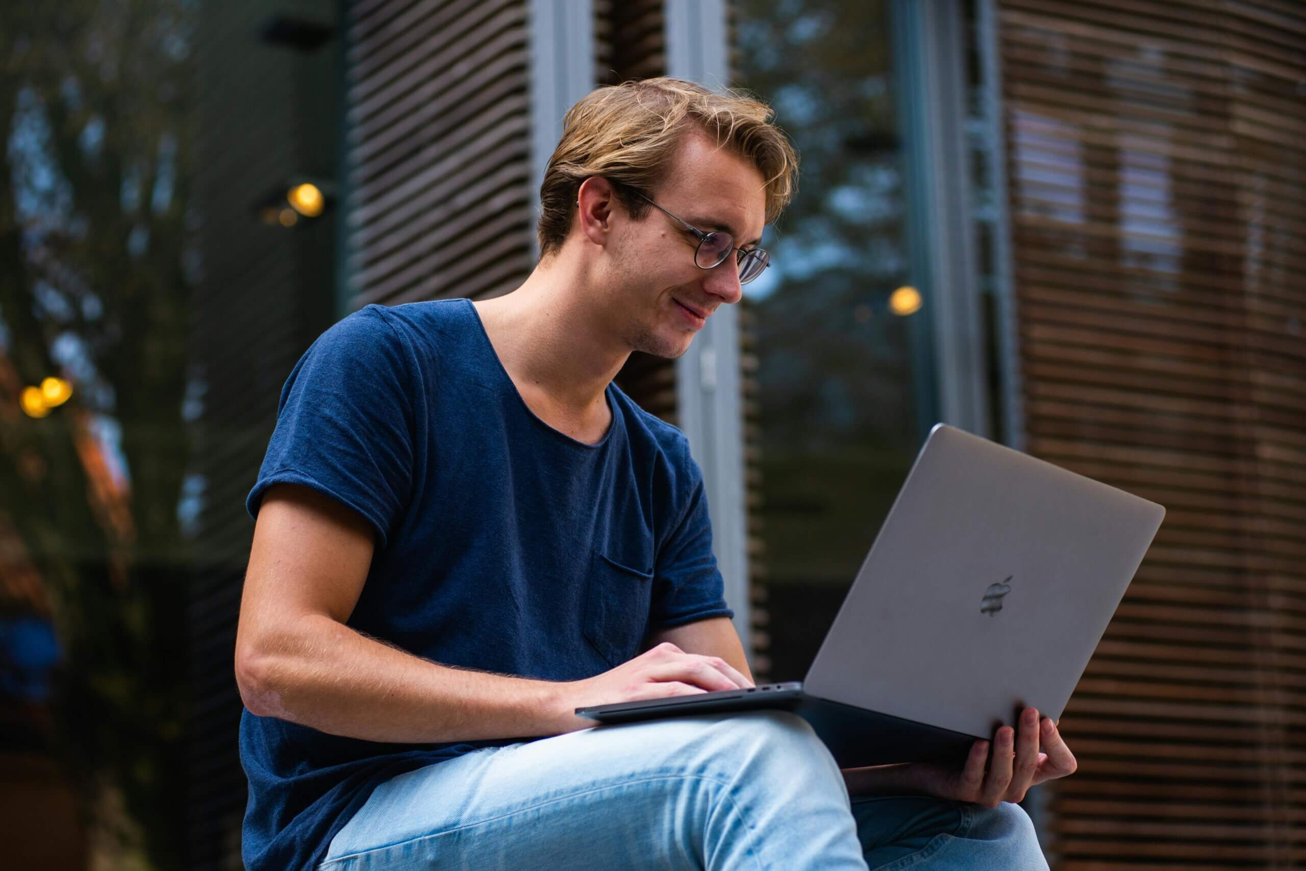 A student checks their laptop outside in the city.