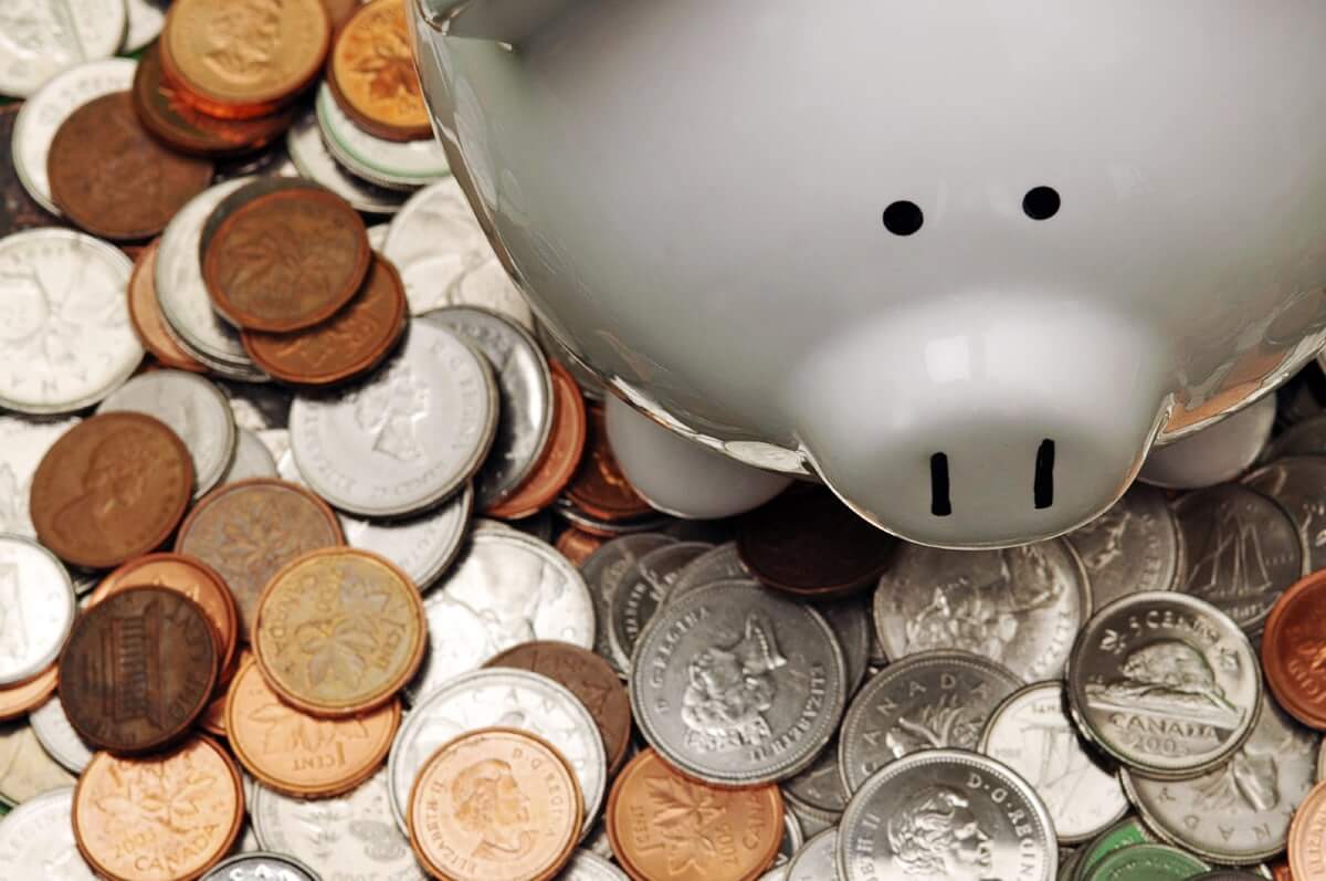A white piggy bank with pennies and other change spread underneath it